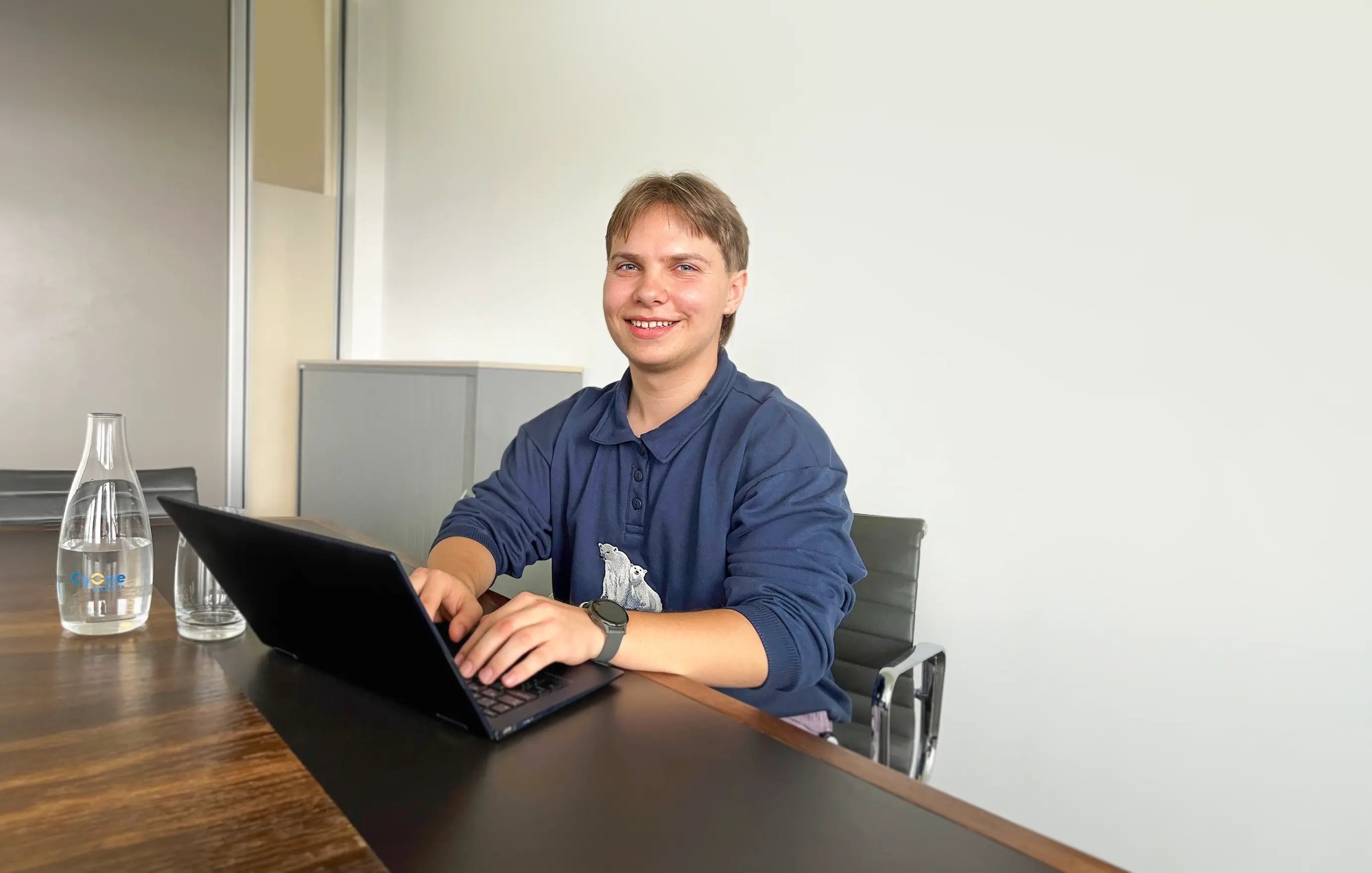 Lernender Aron sitzt im Büro und arbeitet mit einem Notebook