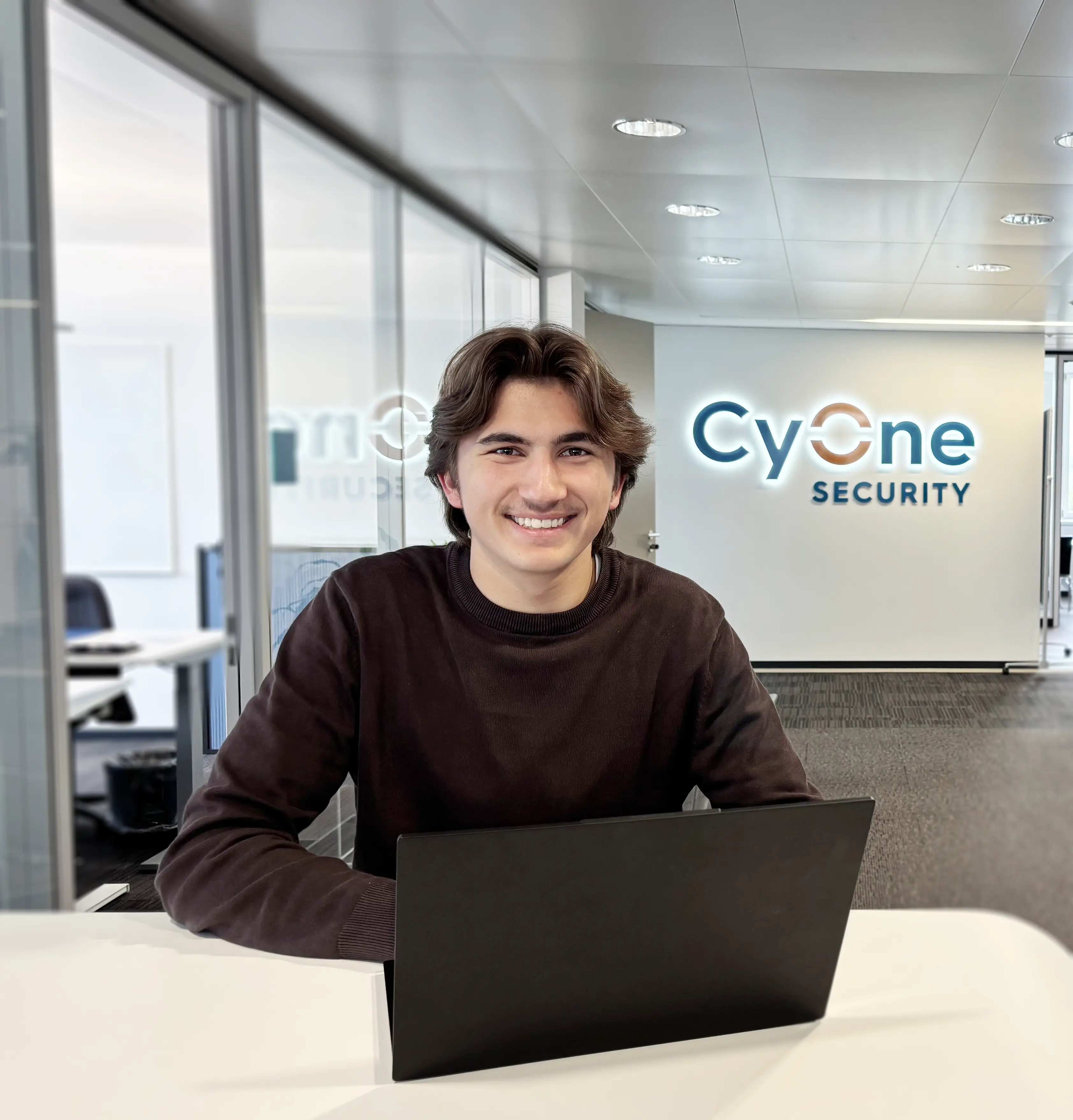 Lernender Leon mit CyOne Security Logo im Hintergrund